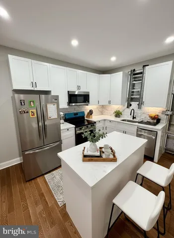 a kitchen with a refrigerator a stove a sink dishwasher and a dining table with wooden floor