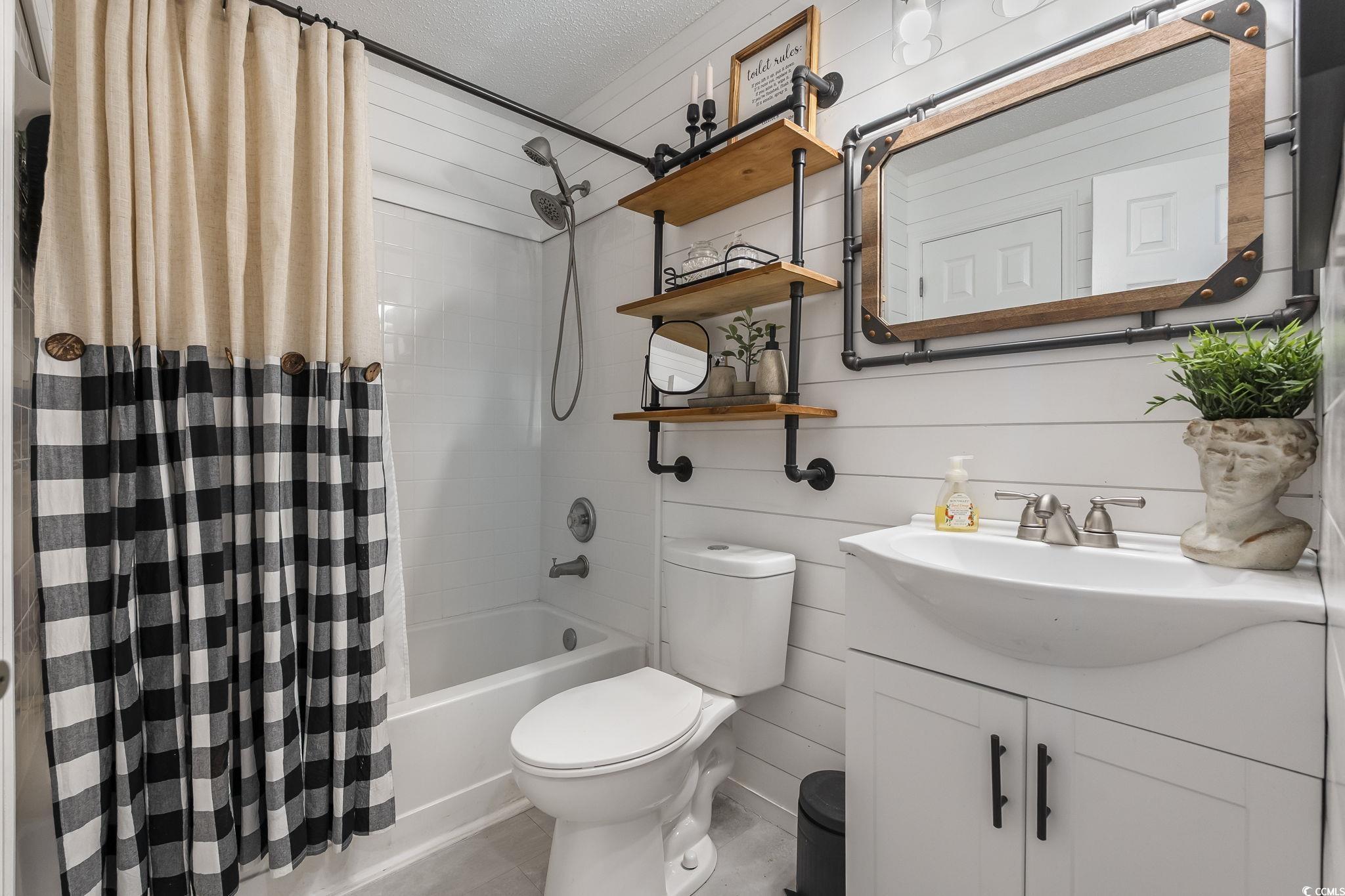 3753 Citation Way, Unit 438 Myrtle Beach, SC 29577 - Photo 23 of 33 Full bath with vanity, shower / bath combination with curtain, a textured ceiling, and wooden walls
