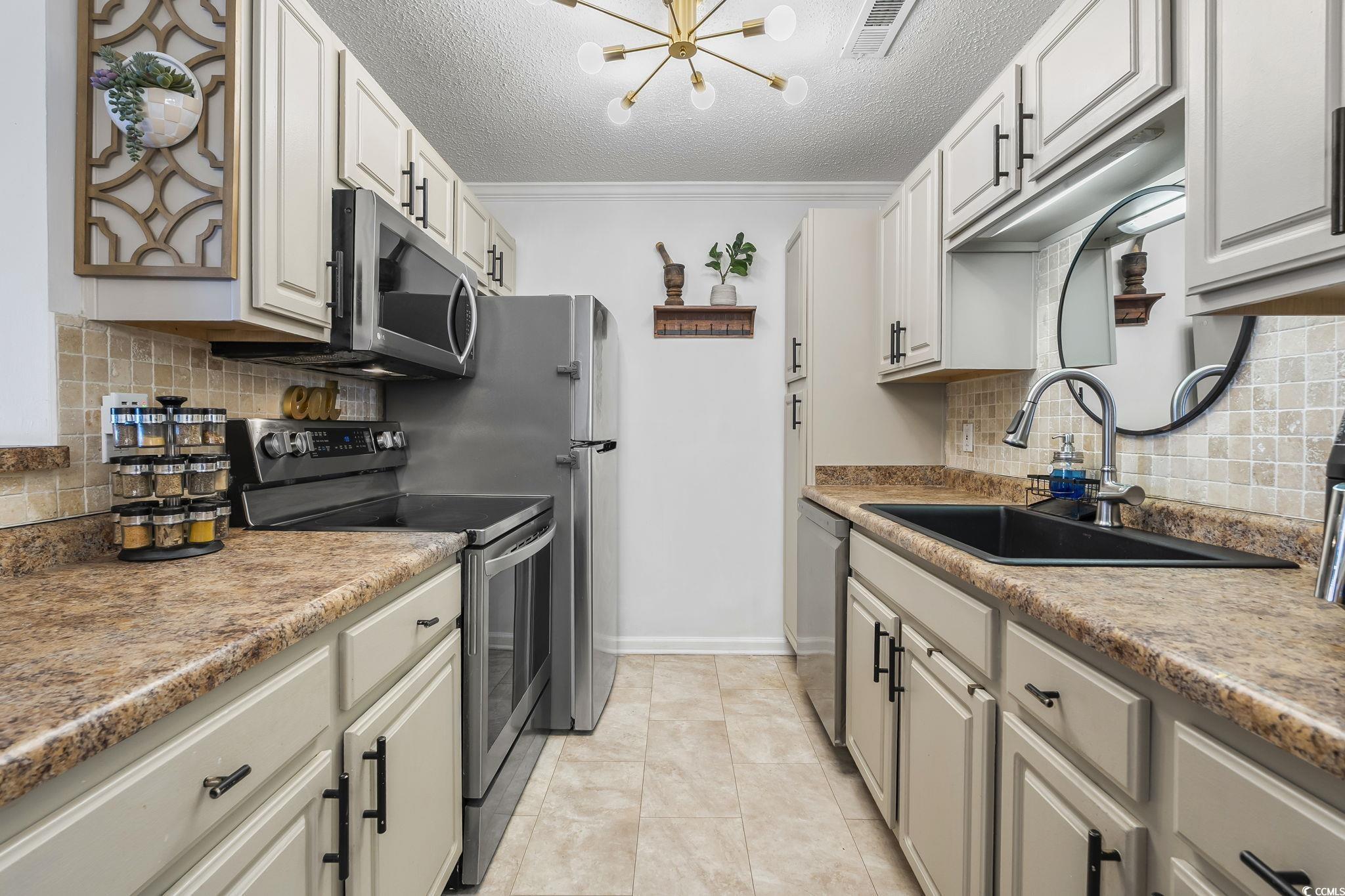 3753 Citation Way, Unit 438 Myrtle Beach, SC 29577 - Photo 6 of 33 Kitchen featuring appliances with stainless steel finishes, backsplash, a chandelier, ornamental molding, and a textured ceiling