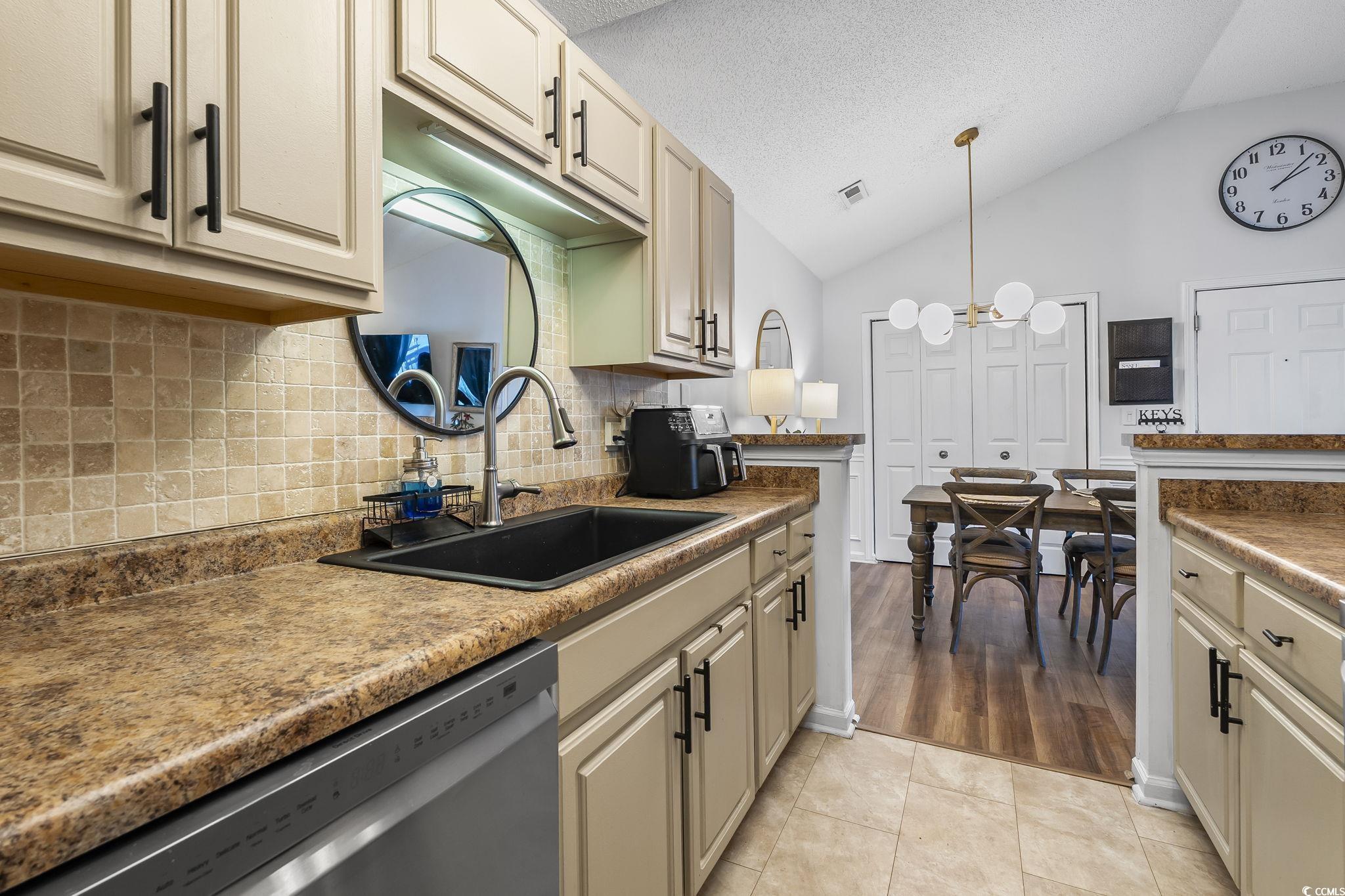 3753 Citation Way, Unit 438 Myrtle Beach, SC 29577 - Photo 9 of 33 Kitchen with vaulted ceiling, tasteful backsplash, stainless steel dishwasher, a textured ceiling, and decorative light fixtures