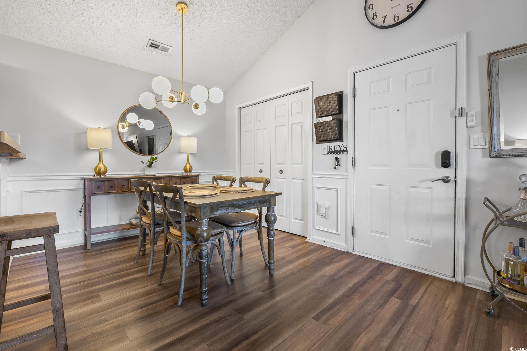 3753 Citation Way, Unit 438 Myrtle Beach, SC 29577 - Photo 10 of 33 Dining area featuring vaulted ceiling, a textured ceiling, dark wood-type flooring, a chandelier, and a wainscoted wall