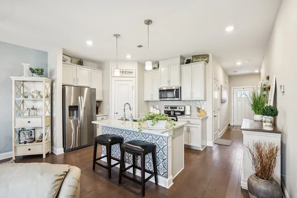 a kitchen with stainless steel appliances granite countertop a refrigerator a stove top oven a dining table and chairs with wooden floor