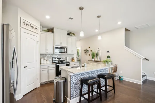 a kitchen with stainless steel appliances granite countertop a table chairs stove and refrigerator