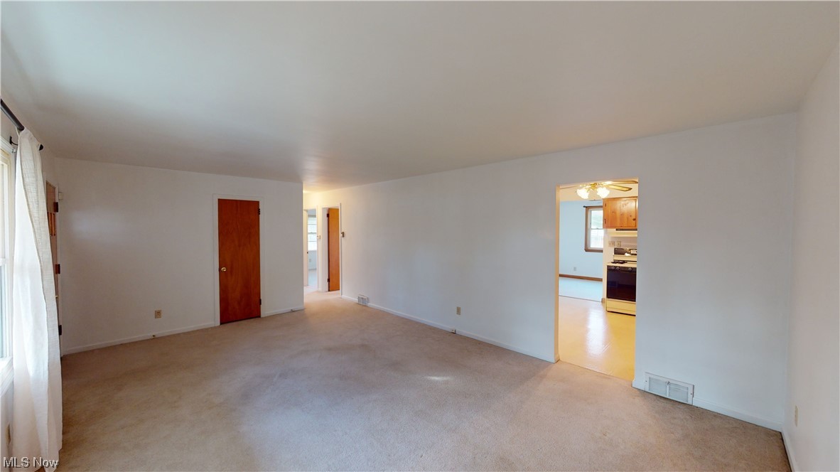 Empty room featuring light carpet and ceiling fan