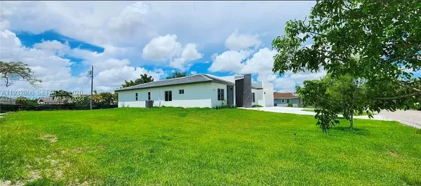 a front view of a house with garden and a tree