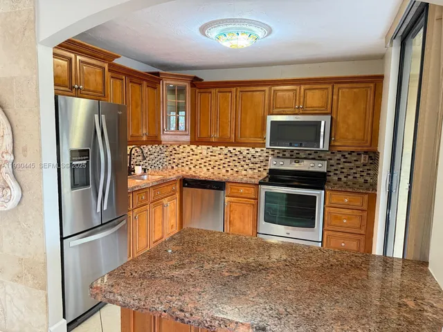 a kitchen with granite countertop a refrigerator stove and sink