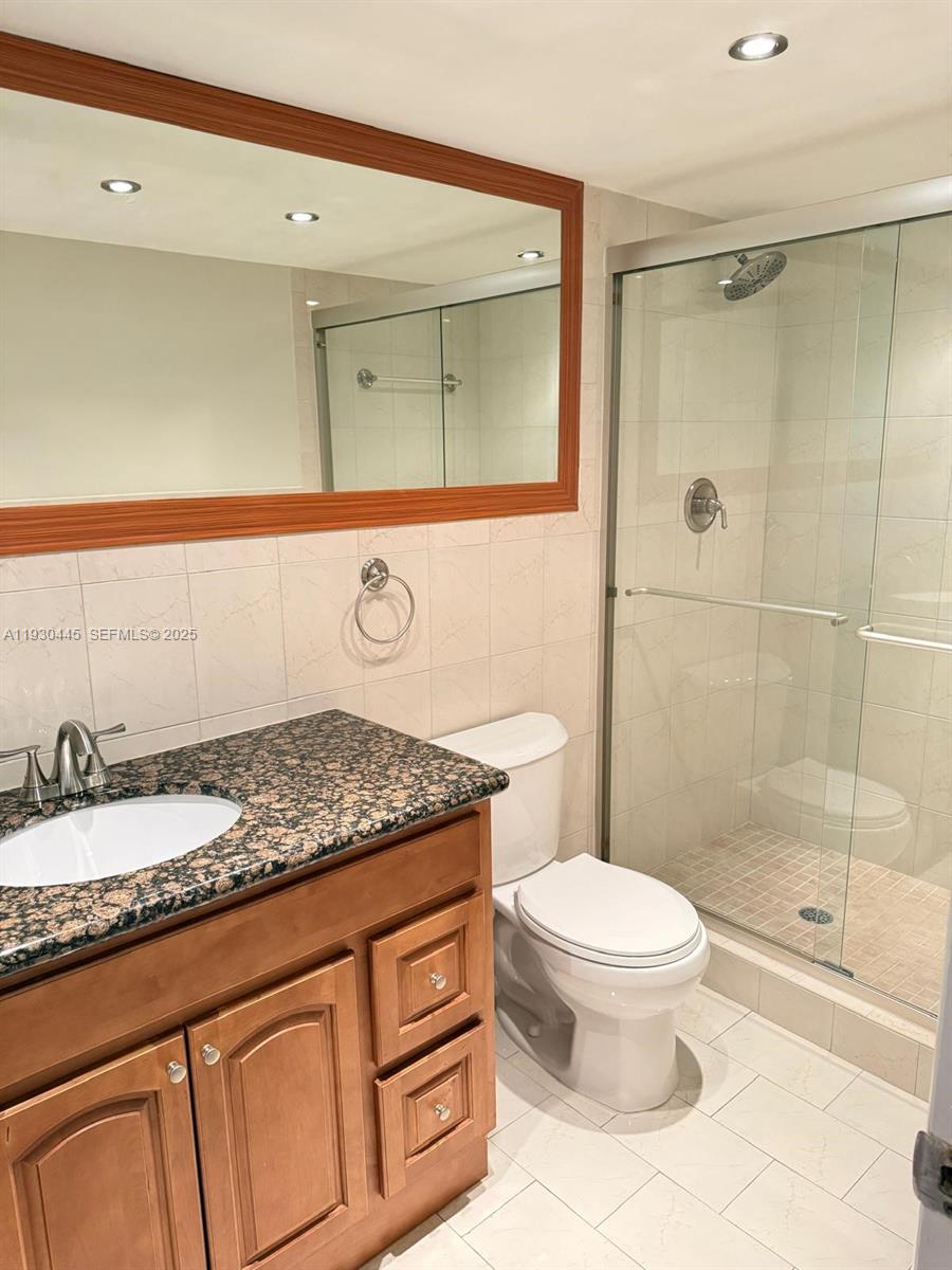 671 Northeast 195th Street, Unit 121E Miami, FL 33179 - Photo 34 of 39 a bathroom with a granite countertop sink mirror vanity and toilet