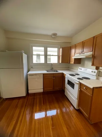 a white kitchen with a sink and wooden floor