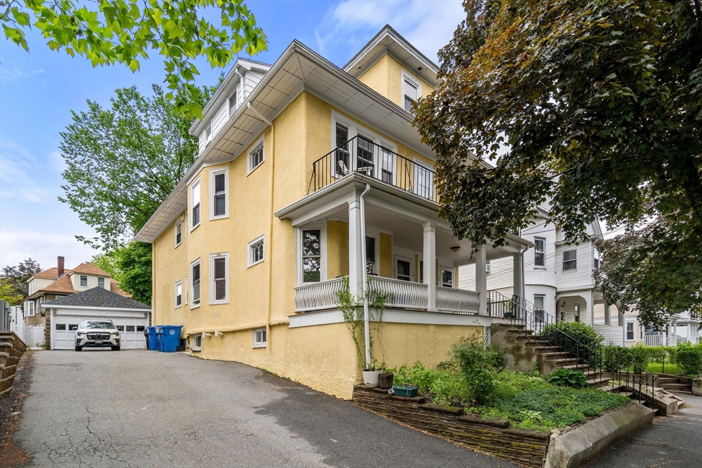 18 Park Road, Unit 1 Belmont, MA 02478 - Photo 3 of 36 a view of a white house with a large windows and a yard with plants and large trees