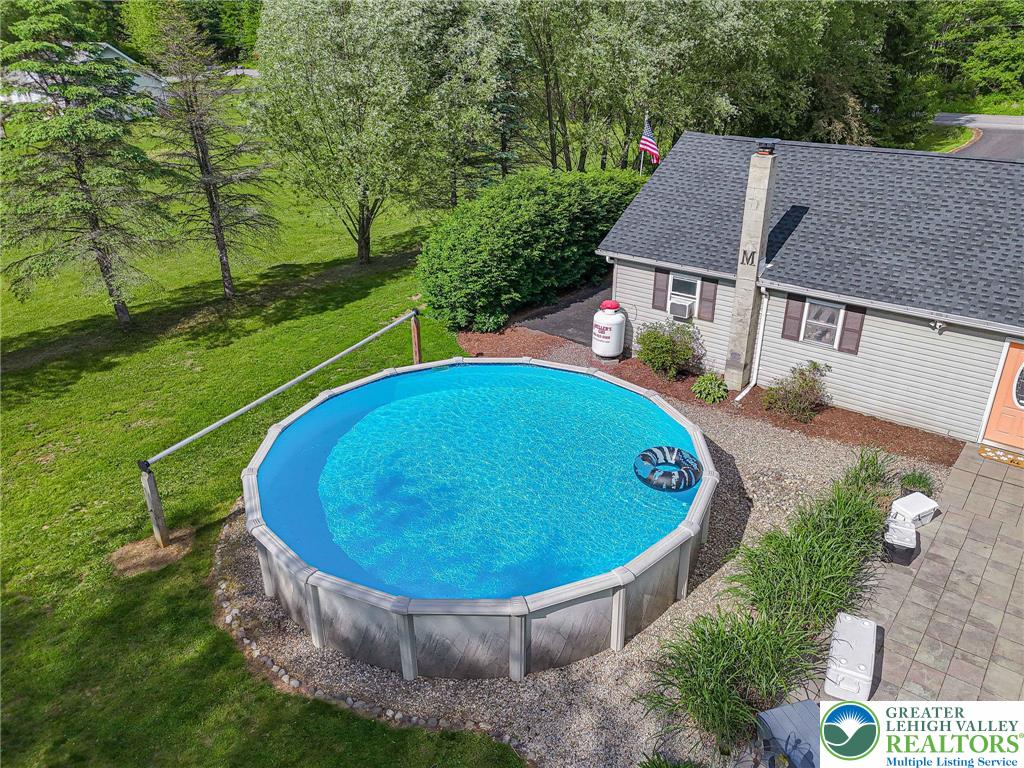 341 Lower Greenhill Road Kunkletown, PA 18058 - Photo 55 of 69 An inviting above-ground pool sits adjacent to a charming residence, surrounded by lush green grounds and mature trees.