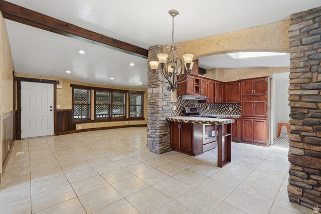 2875 North Hill Field Road, Unit 111 Layton, UT 84041 - Photo 1 of 30 Kitchen with glass insert cabinets, a chandelier, stainless steel range with gas cooktop, light countertops, and beam ceiling