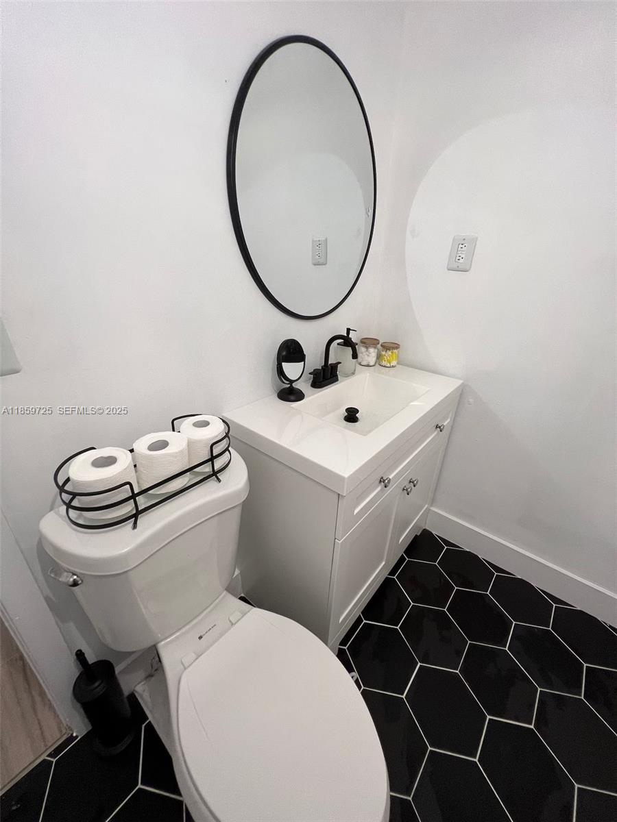 2701 Northwest 24th Court, Unit R Miami, FL 33142 - Photo 4 of 20 a bathroom with a toilet a sink and a mirror