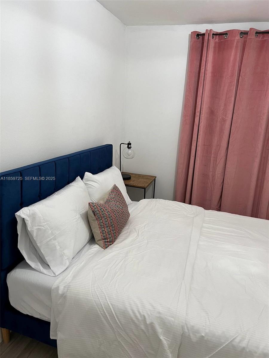 2701 Northwest 24th Court, Unit R Miami, FL 33142 - Photo 8 of 20 a bedroom with a bed and wooden floor