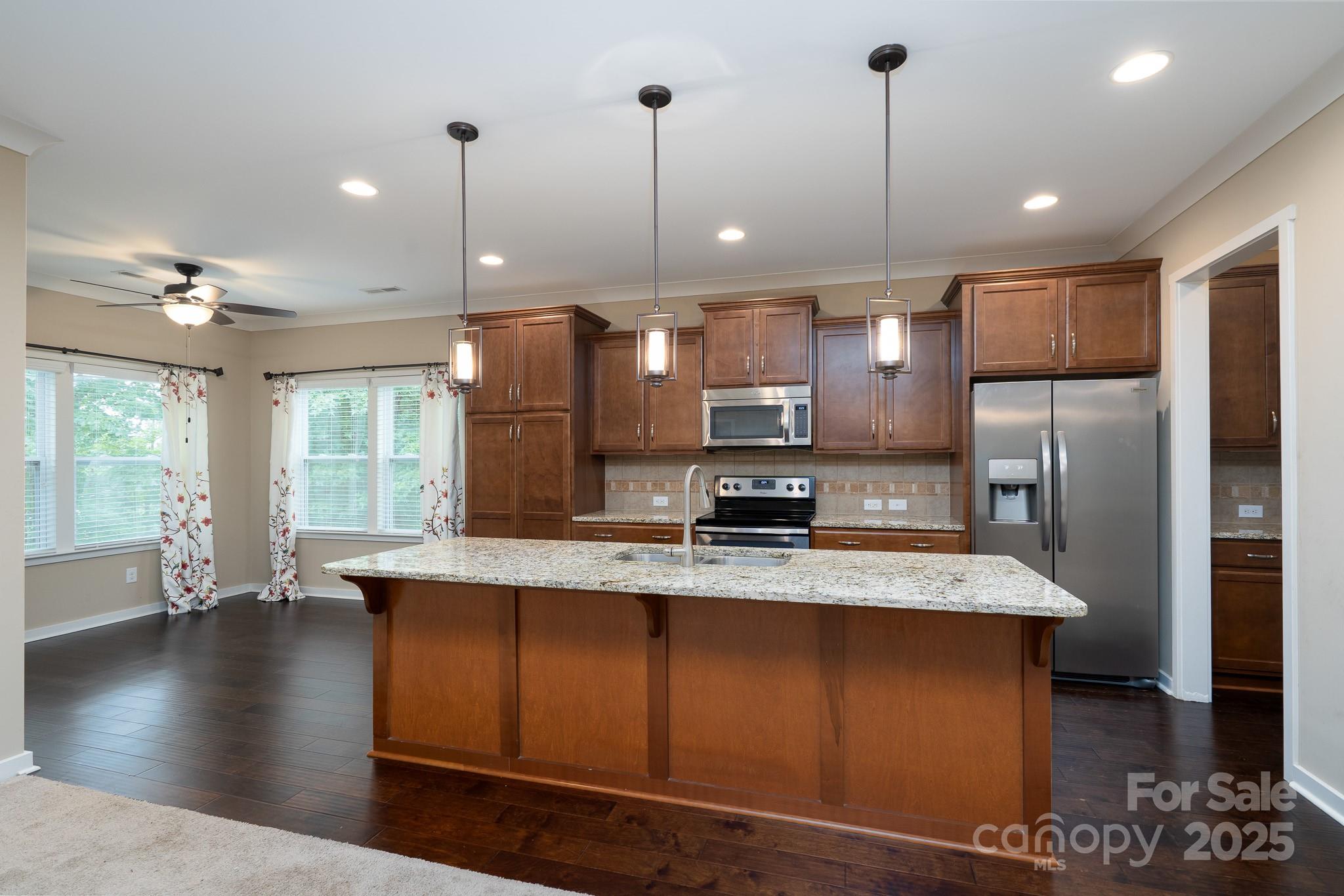 2496 Bergamot Street, Unit 61 Tega Cay, SC 29708 - Photo 11 of 43 a large kitchen with stainless steel appliances kitchen island granite countertop a refrigerator a oven a sink and a wooden floors