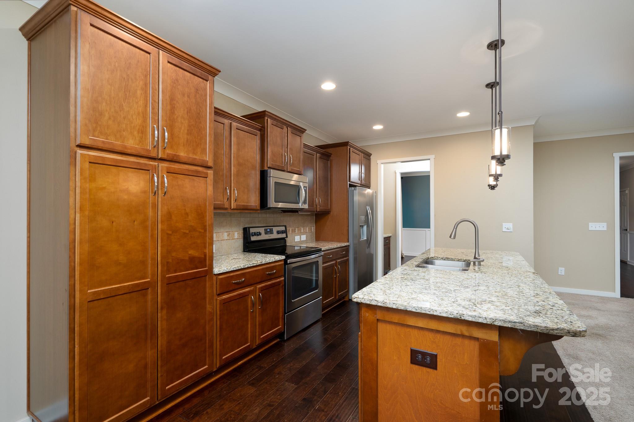 2496 Bergamot Street, Unit 61 Tega Cay, SC 29708 - Photo 12 of 43 a kitchen with kitchen island granite countertop wooden cabinets and refrigerator