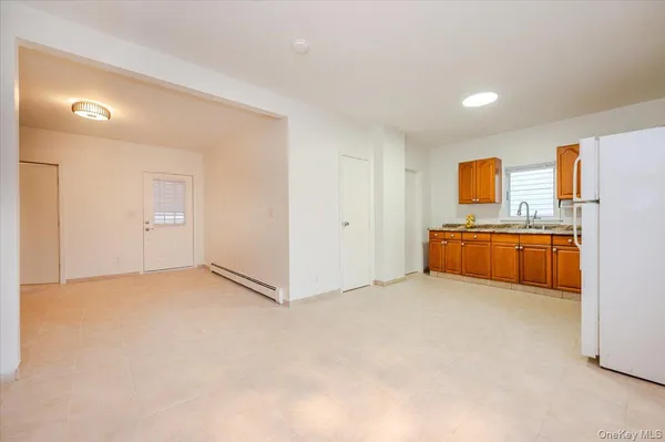 a view of an empty room with window and a kitchen