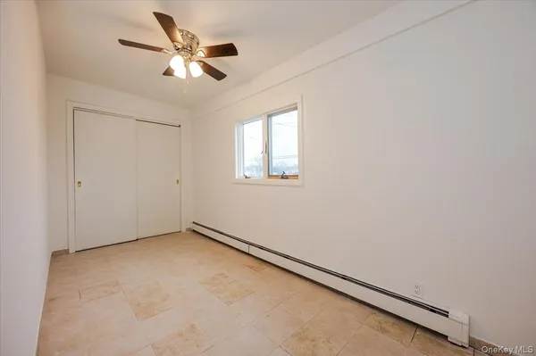 an empty room with a window and a ceiling fan