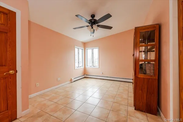 a view of an empty room with cabinet and a ceiling fan