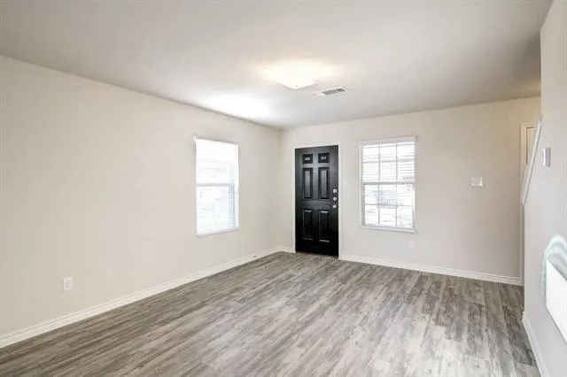 a view of an empty room with a window and wooden floor