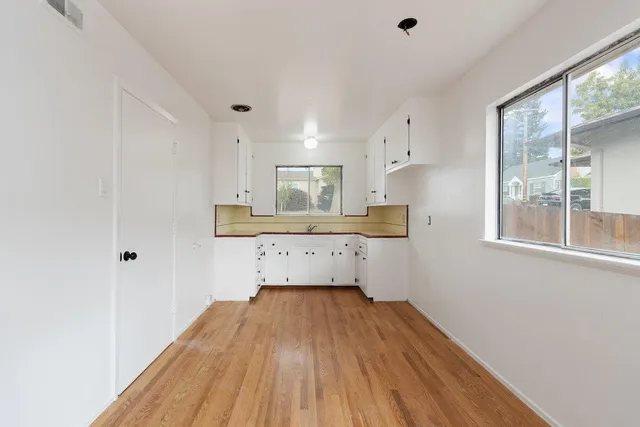 a room with kitchen island a sink wooden floor and view living room