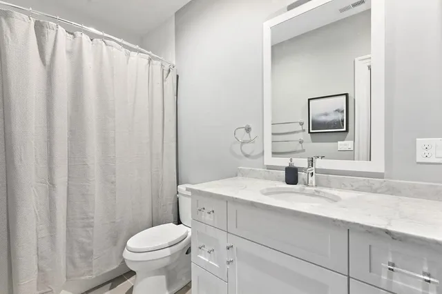 a bathroom with a sink vanity mirror and toilet