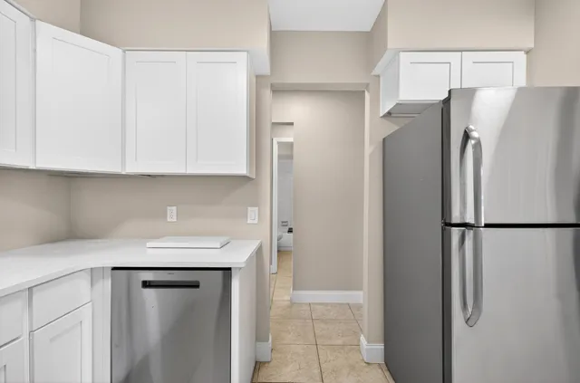 a view of a kitchen with a refrigerator and an empty table