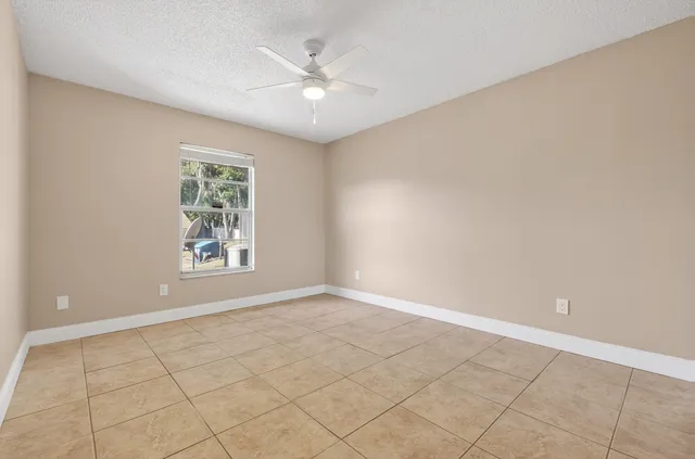 an empty room with a ceiling fan and glass door
