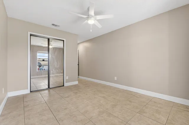 an empty room with a ceiling fan and a window