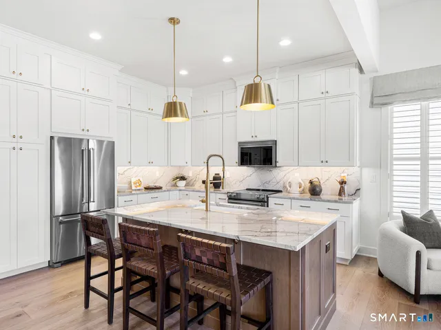 a kitchen with a refrigerator a stove a sink and a dining table with wooden floor