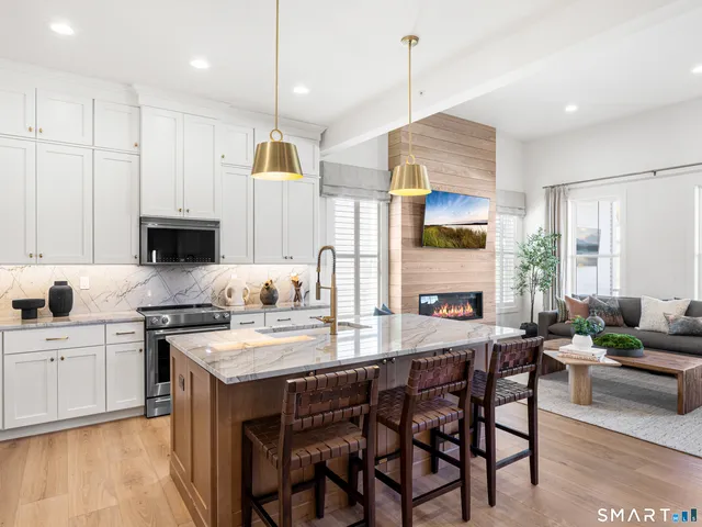 a kitchen with stainless steel appliances kitchen island granite countertop a stove a sink a oven a dining table and chairs