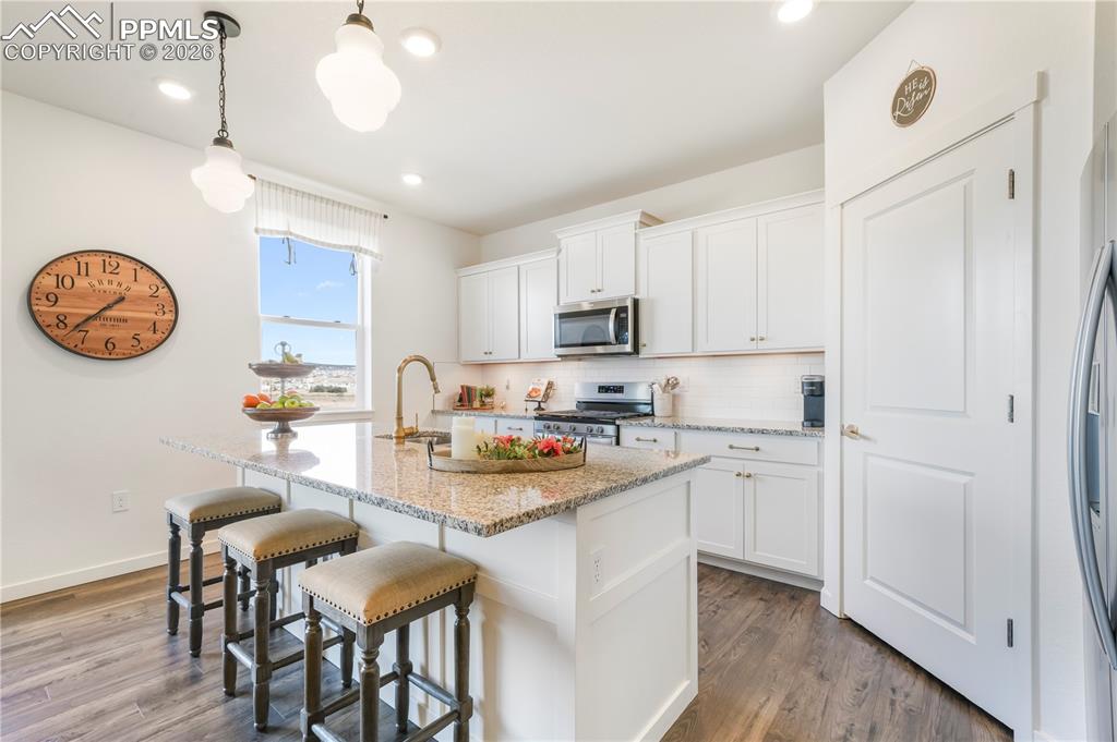 15882 Little Bluestem Road Monument, CO 80132 - Photo 10 of 50 Kitchen with gas range, stainless appliances, walk in pantry, granite countertops, large center island, under cabinet lighting