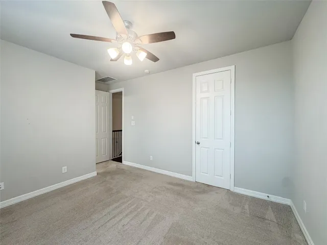 an empty room with closet and a ceiling fan