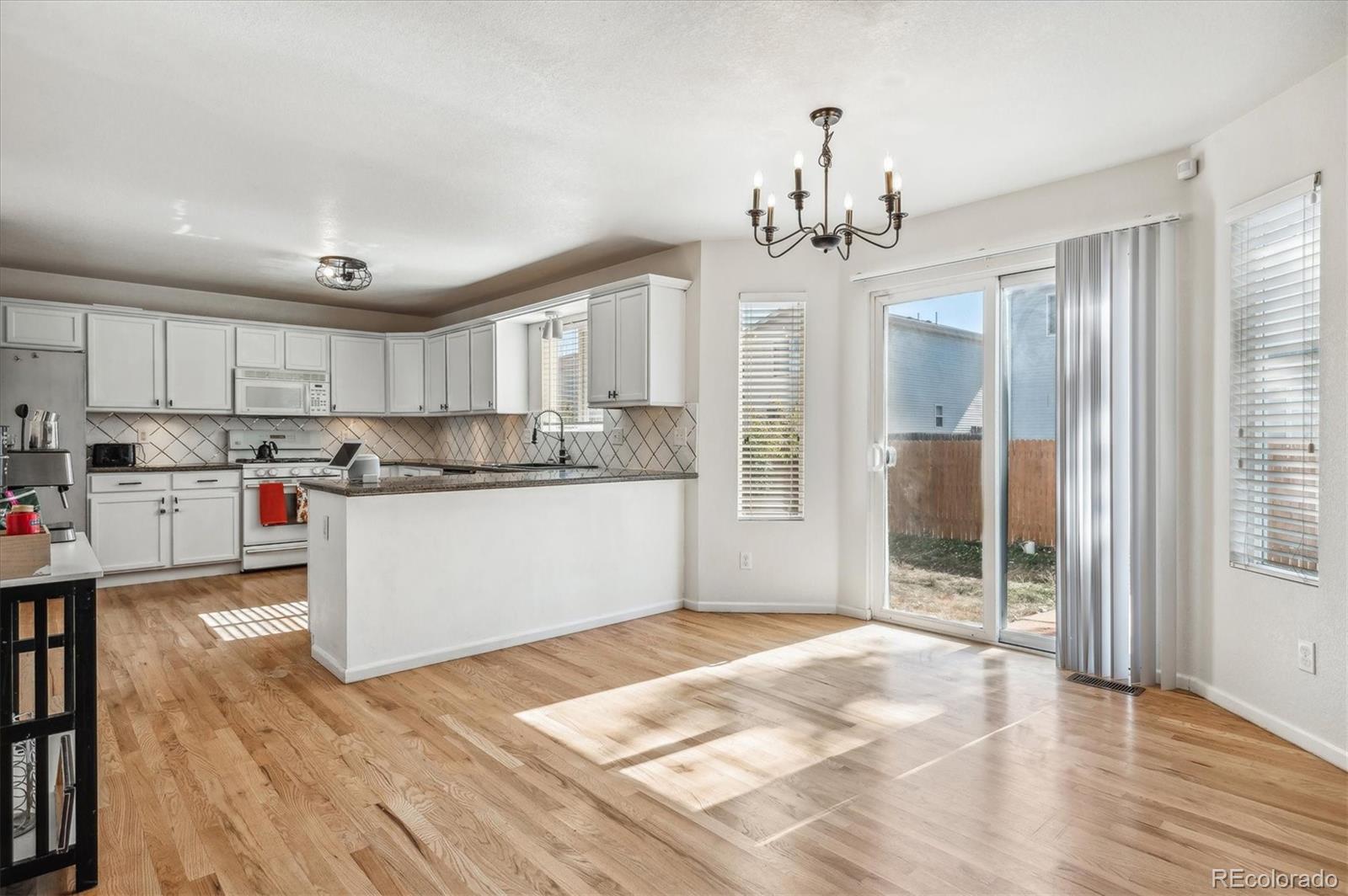 1345 Trail Ridge Road Longmont, CO 80504 - Photo 7 of 25 a kitchen with stainless steel appliances granite countertop a refrigerator a sink dishwasher a stove and white cabinets with wooden floor
