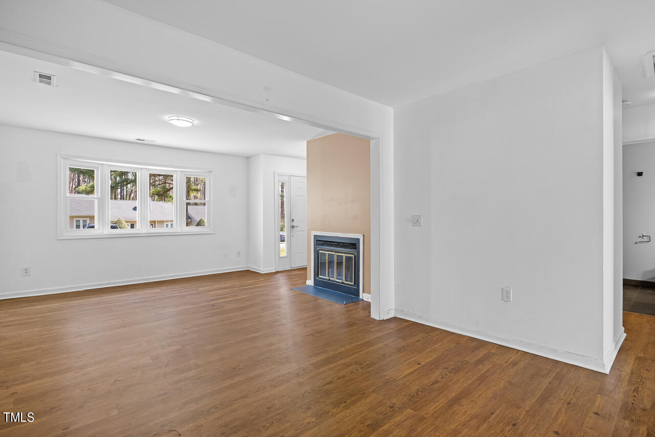 7604 Ladden Court Raleigh, NC 27615 - Photo 6 of 29 an empty room with wooden floor fireplace and windows