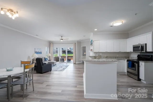 a living room with stainless steel appliances granite countertop furniture wooden floor and a kitchen view