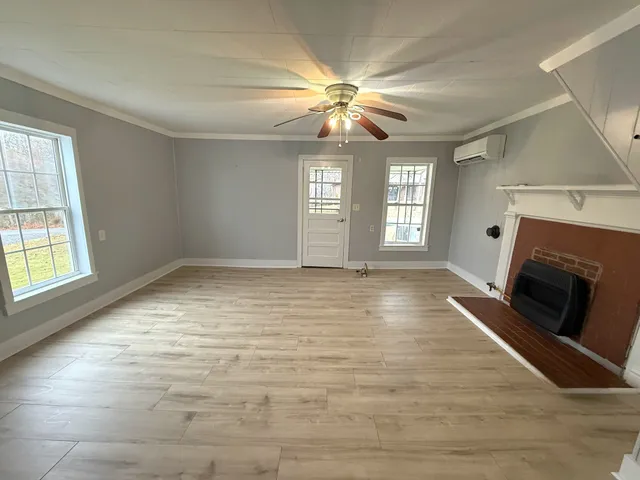 a view of an empty room with window and fire place