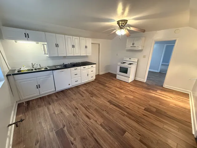 a kitchen with granite countertop a stove a sink and a refrigerator