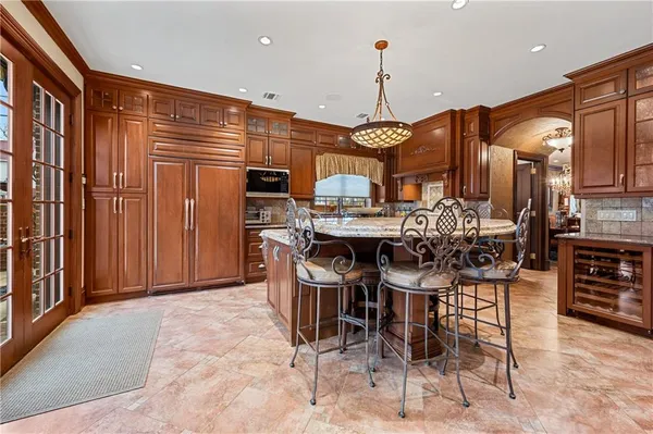 a view of a kitchen with stainless steel appliances kitchen island granite countertop a refrigerator a stove a sink with a dining table and chairs