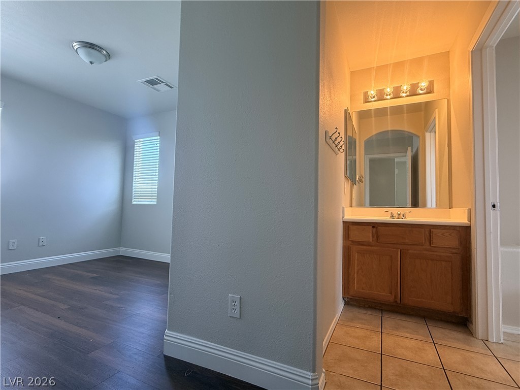 11953 Fairfax Ridge Street Las Vegas, NV 89183 - Photo 12 of 32 A compact vanity with warm lighting and ample storage complements the adjacent room's rich wood flooring.