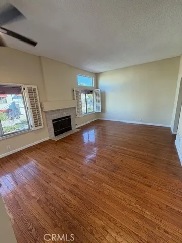 a view of empty room with wooden floor fireplace and window