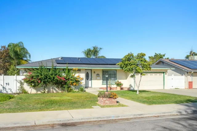 a front view of a house with a yard and potted plants