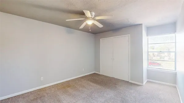 an empty room with window and ceiling fan