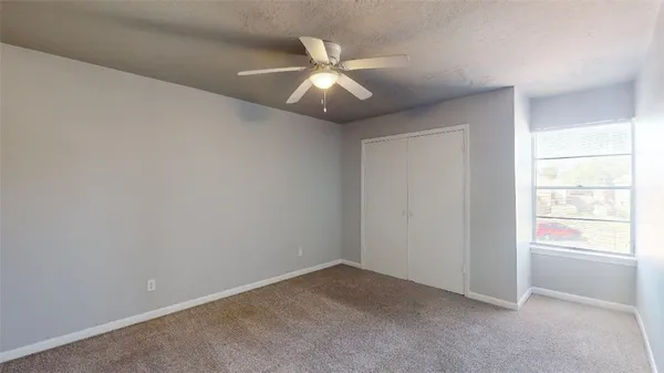 an empty room with window and ceiling fan