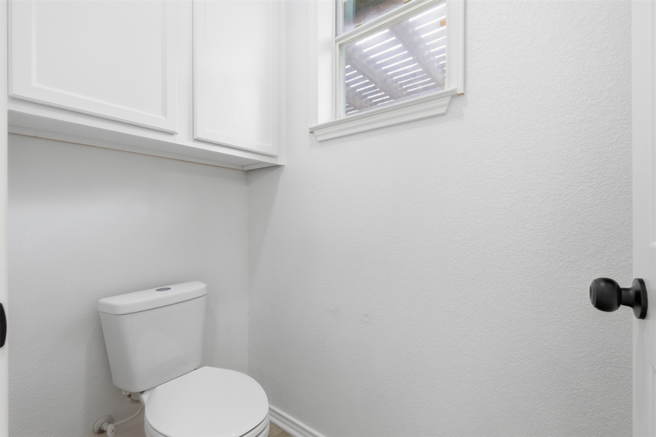 461 Hot Spring Valley Buda, TX 78610 - Photo 14 of 25 The bathroom features a white toilet, white upper cabinets, and a window providing natural light
