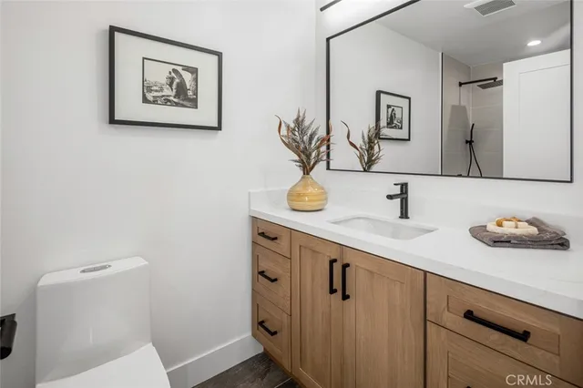 a view of a hallway with wooden floor and a bathroom