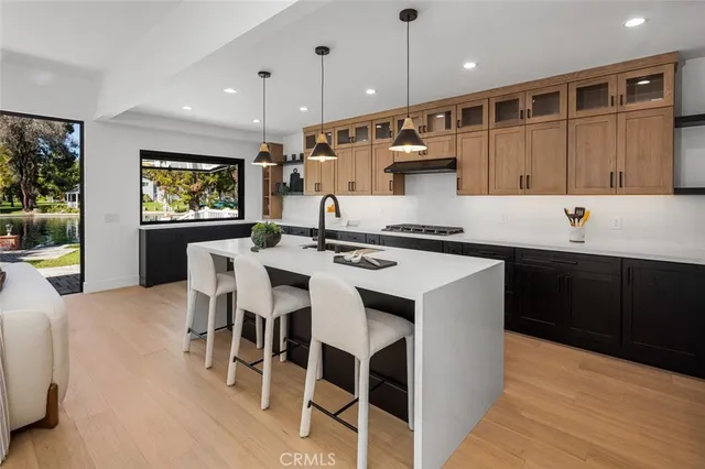 a kitchen with stainless steel appliances kitchen island granite countertop a sink a stove a dining table and chairs