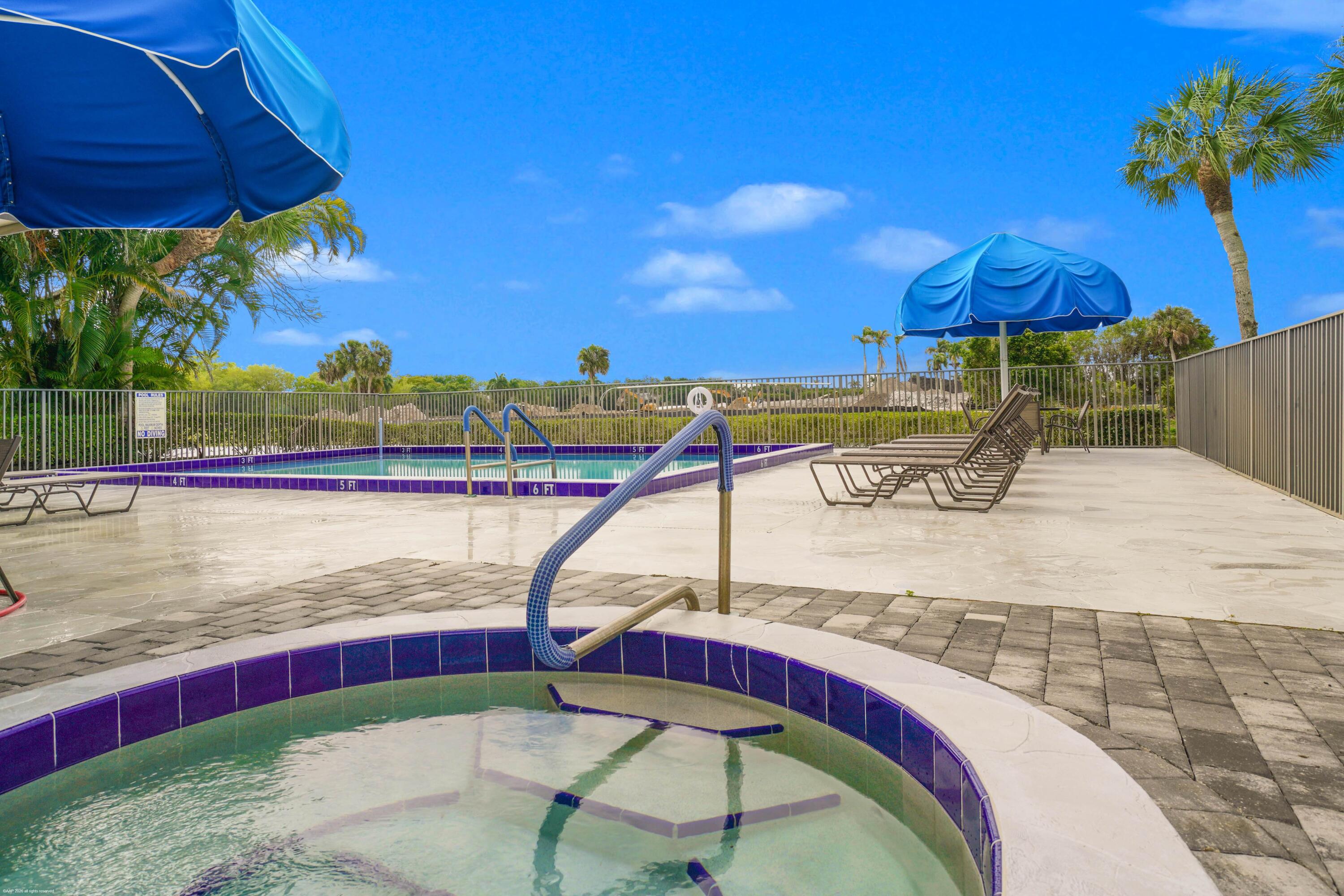 13254 Polo Club Road, Unit C101 Wellington, FL 33414 - Photo 59 of 71 a view of a swimming pool with a table and chairs under an umbrella