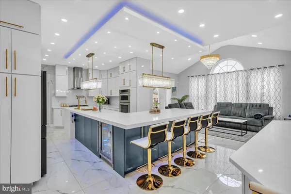 a kitchen with stainless steel appliances kitchen island granite countertop a table chairs refrigerator and microwave