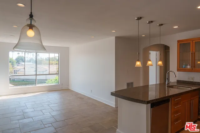 a view of kitchen with granite countertop sink and refrigerator
