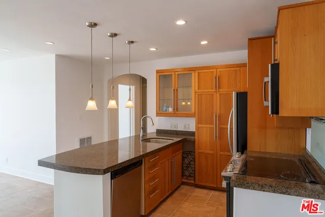 a kitchen with stainless steel appliances granite countertop a sink a stove and a refrigerator
